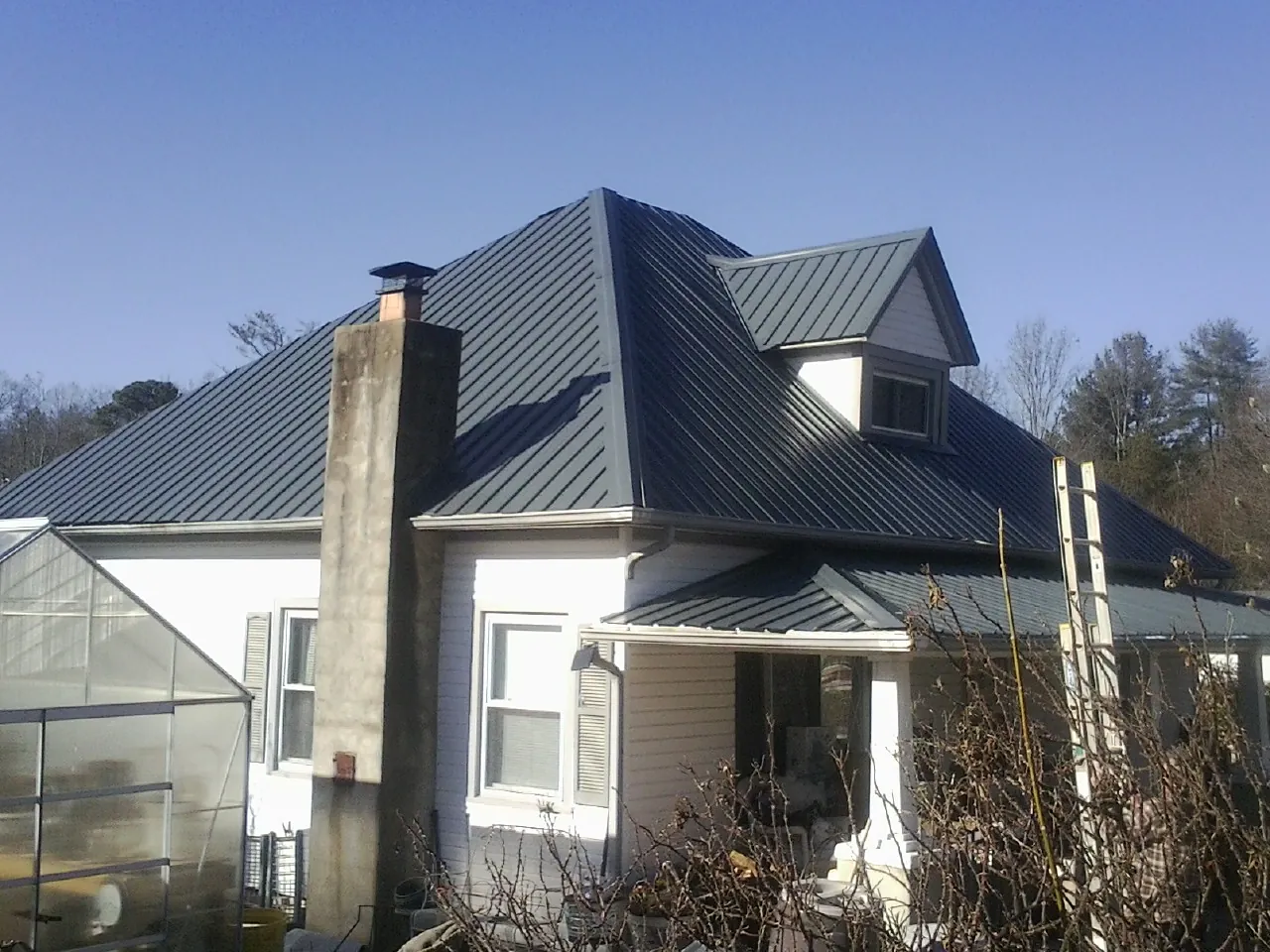 Dark blue standing seam metal roof on a white farmhouse with dormer — Slate & Tile Roof Repair by Roofing Brothers in Absecon
