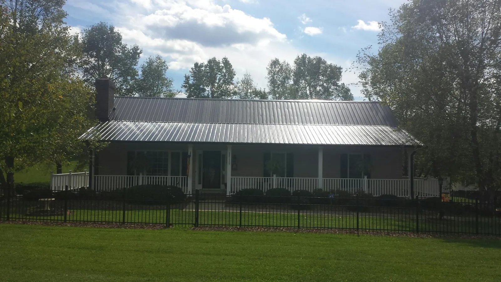 Gray metal roof on a brick ranch with a full width front porch — Gutter Guard Installation work by our crew in Absecon