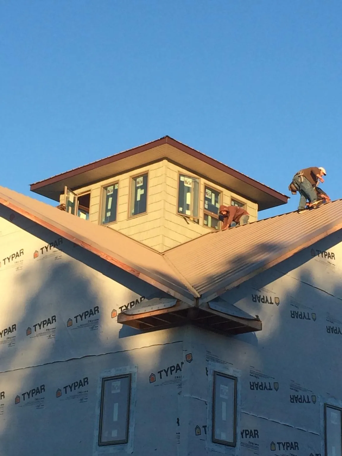 Roofers working around a rooftop cupola on a new metal roof at sunset — Roof Waterproofing in Absecon by Roofing Brothers